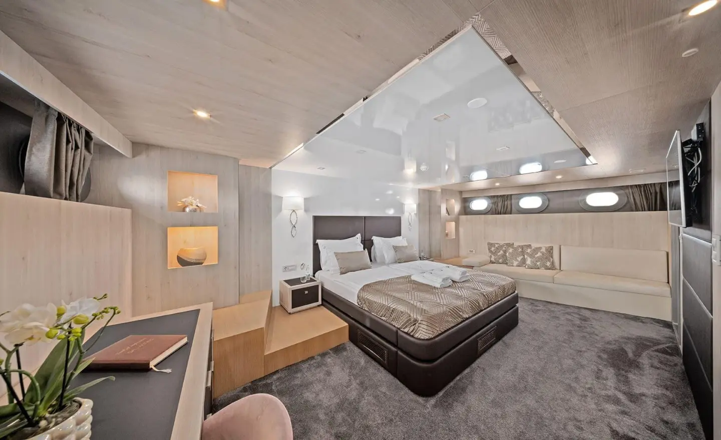 Dalmatino yacht interior with a large bed, seating area, and modern decor