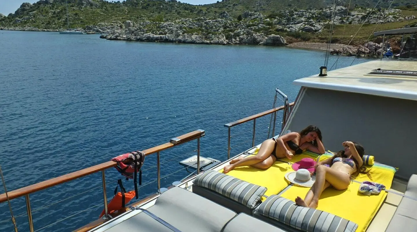 Yacht Kaptan Mehmet Bugra docked with yellow loungers on deck by calm blue water