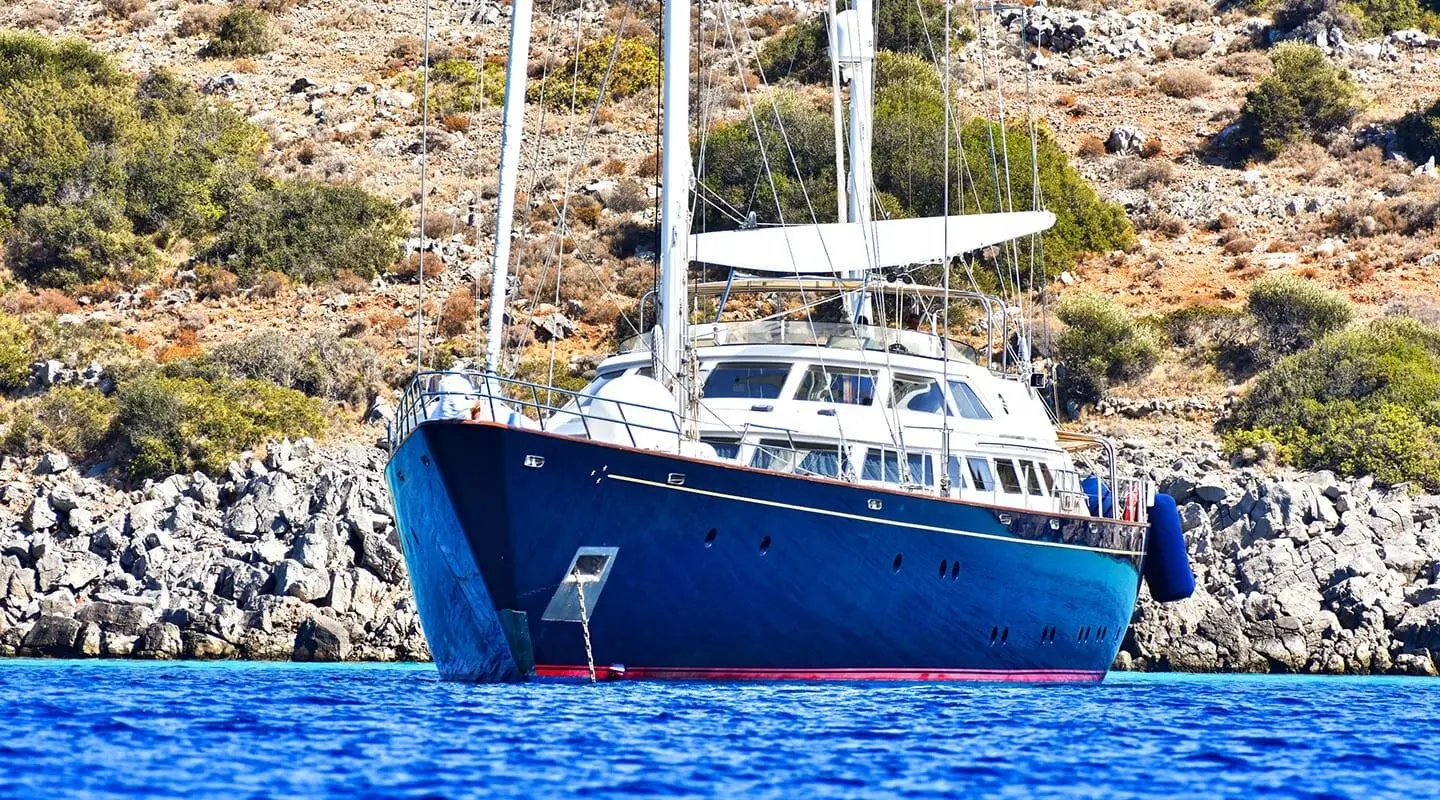 Tamarita yacht anchored in calm blue water; blue hull and white superstructure