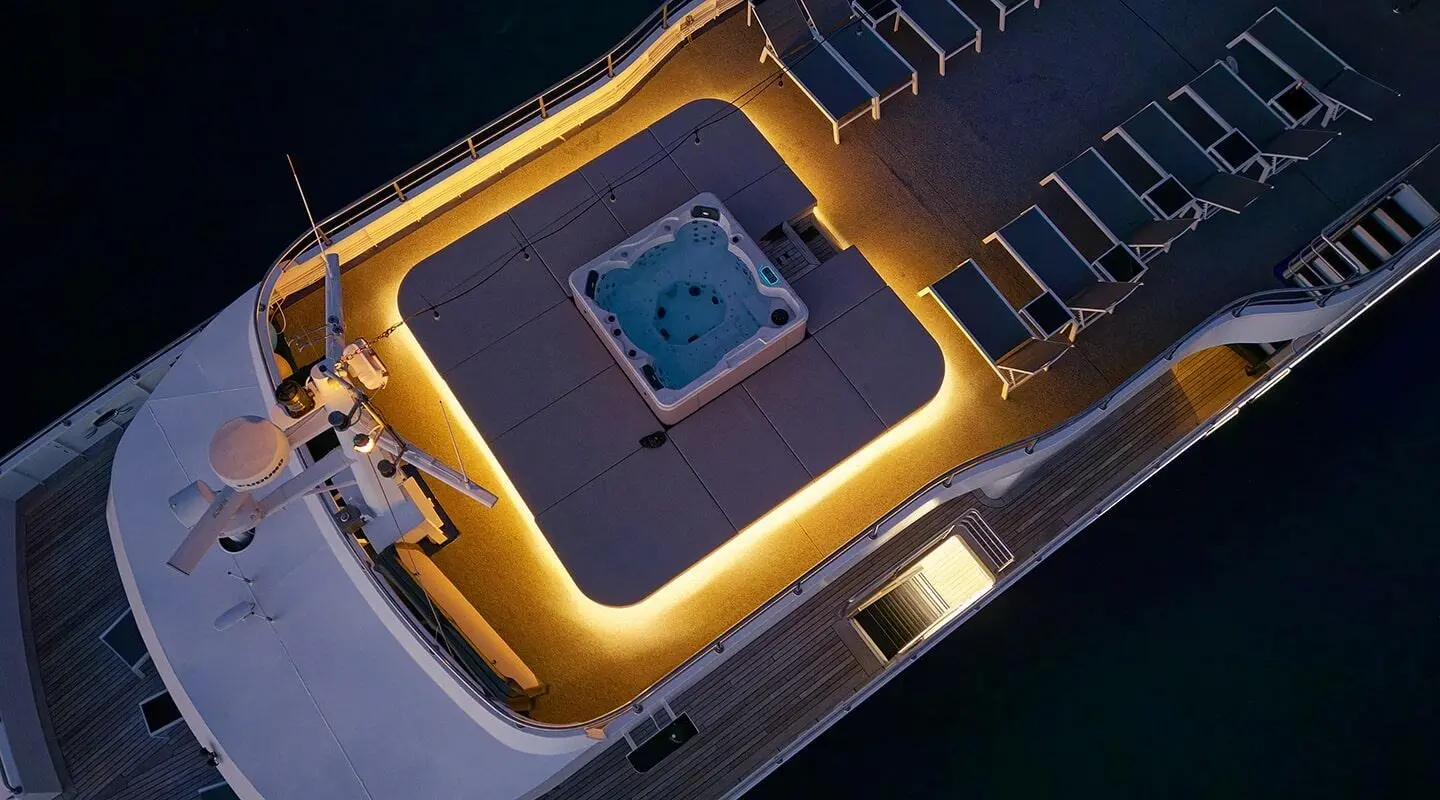 Sun deck of Lupus Mare yacht with hot tub and loungers at sunset