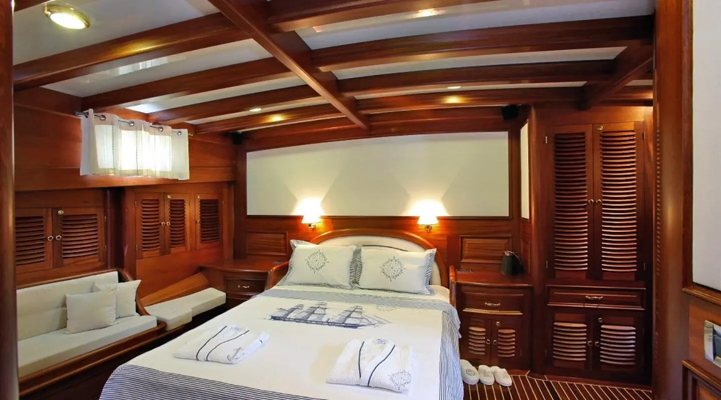 Luxurious cabin with bed and polished wood interior aboard Kaya Guneri 4 yacht at sunset
