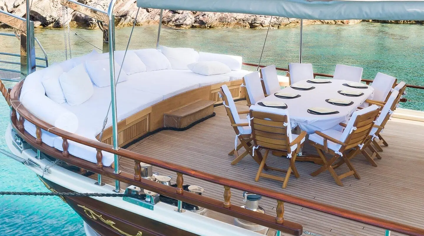 Estrella De Mar yacht deck with sun loungers and dining area at sunset