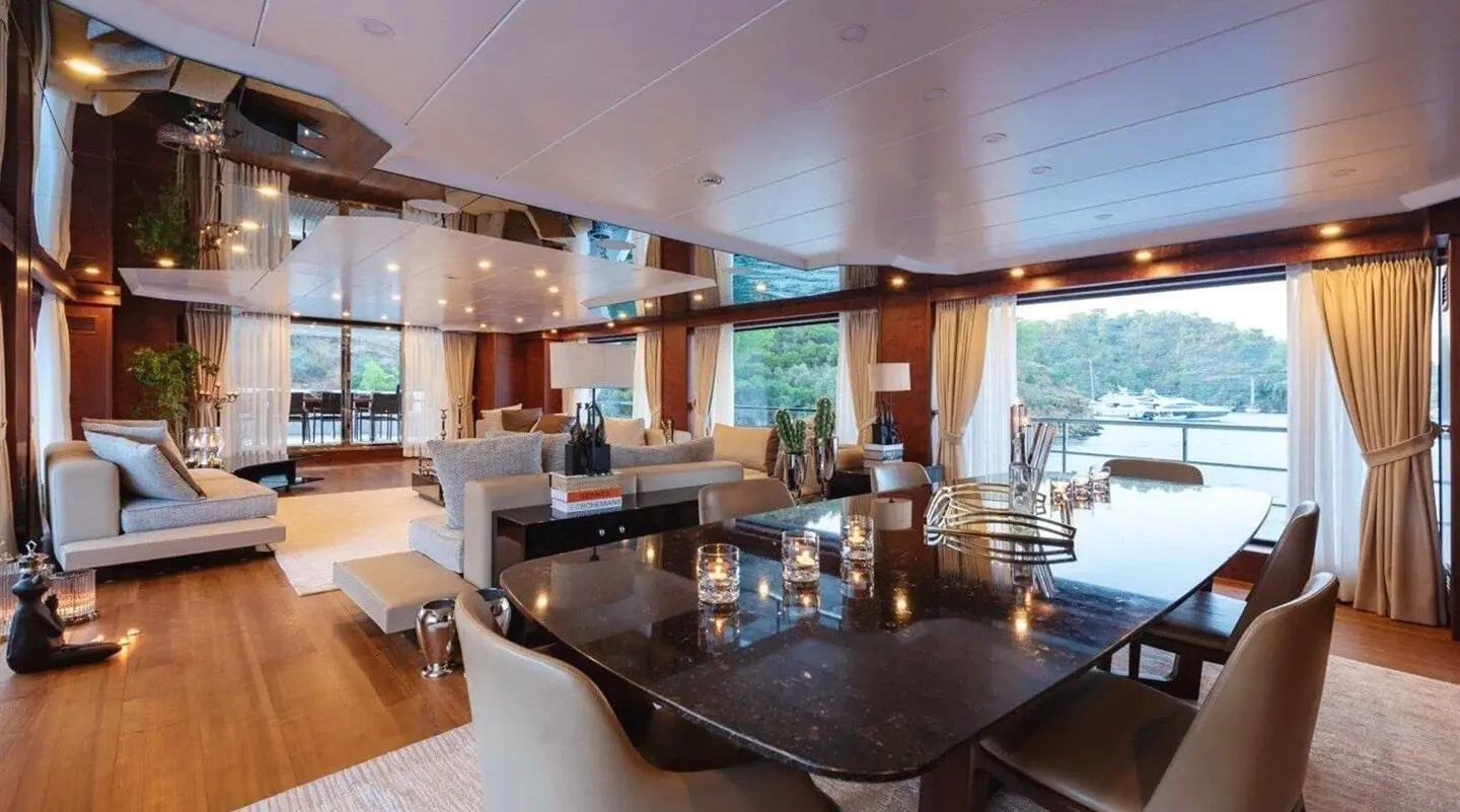 Interior dining lounge aboard Ocean Breeze yacht with dark wood table and seating