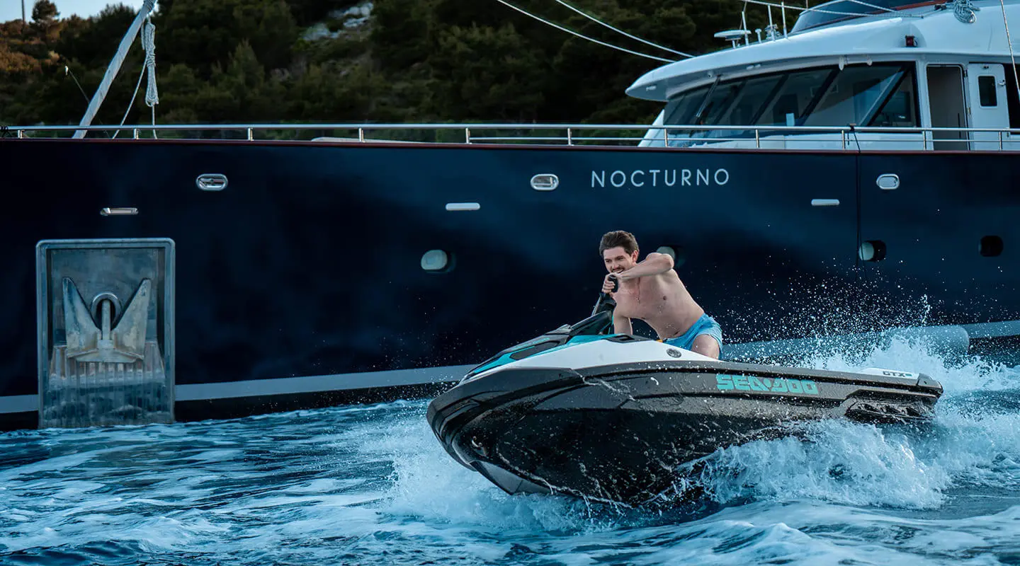 Person riding a Seadoo jetski beside the Nocturno yacht