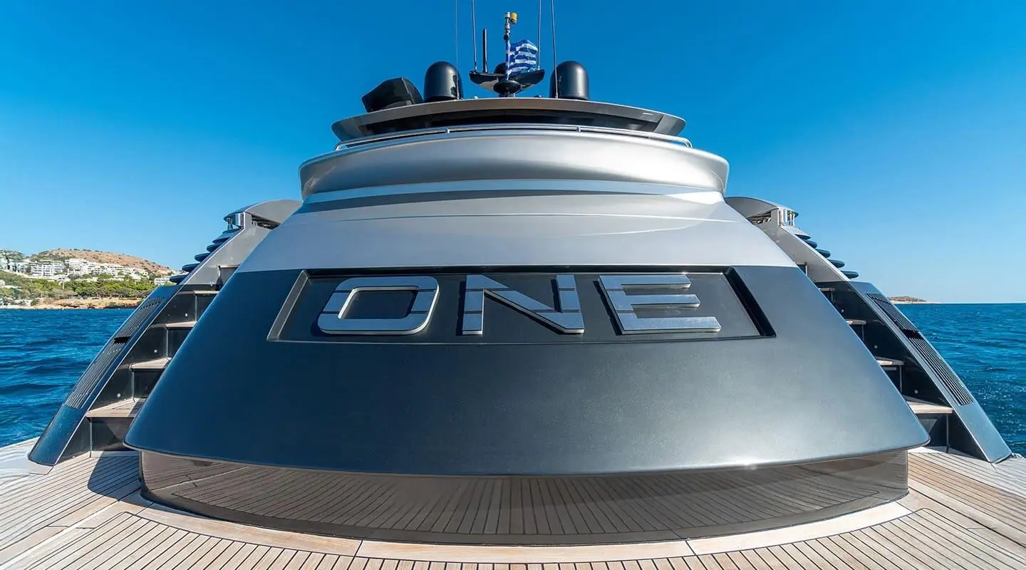 Close-up view of the yacht One's bow with large hull logo and deck lines