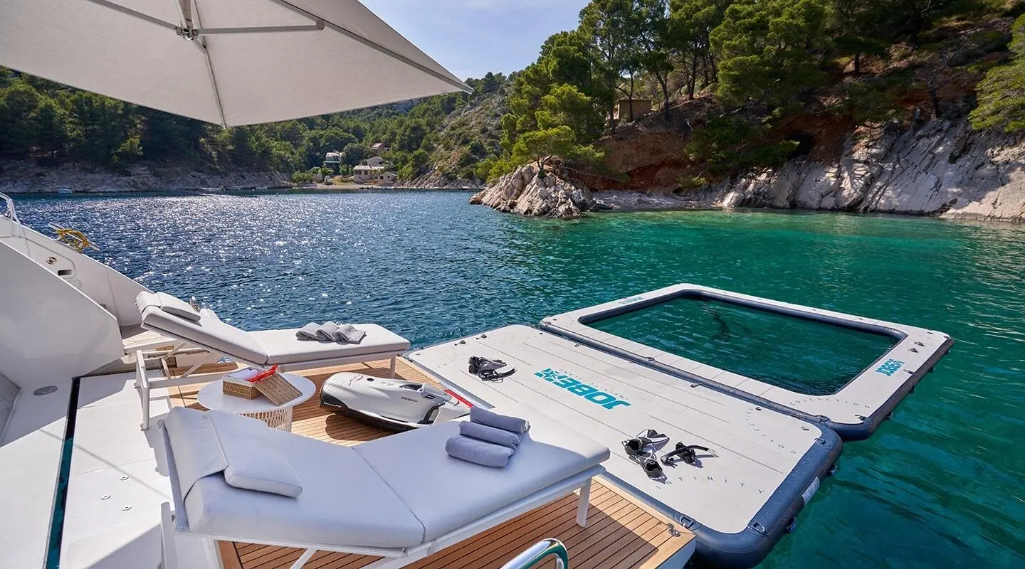 Aluminia Too yacht at sunset docked by turquoise water and rocky coastline