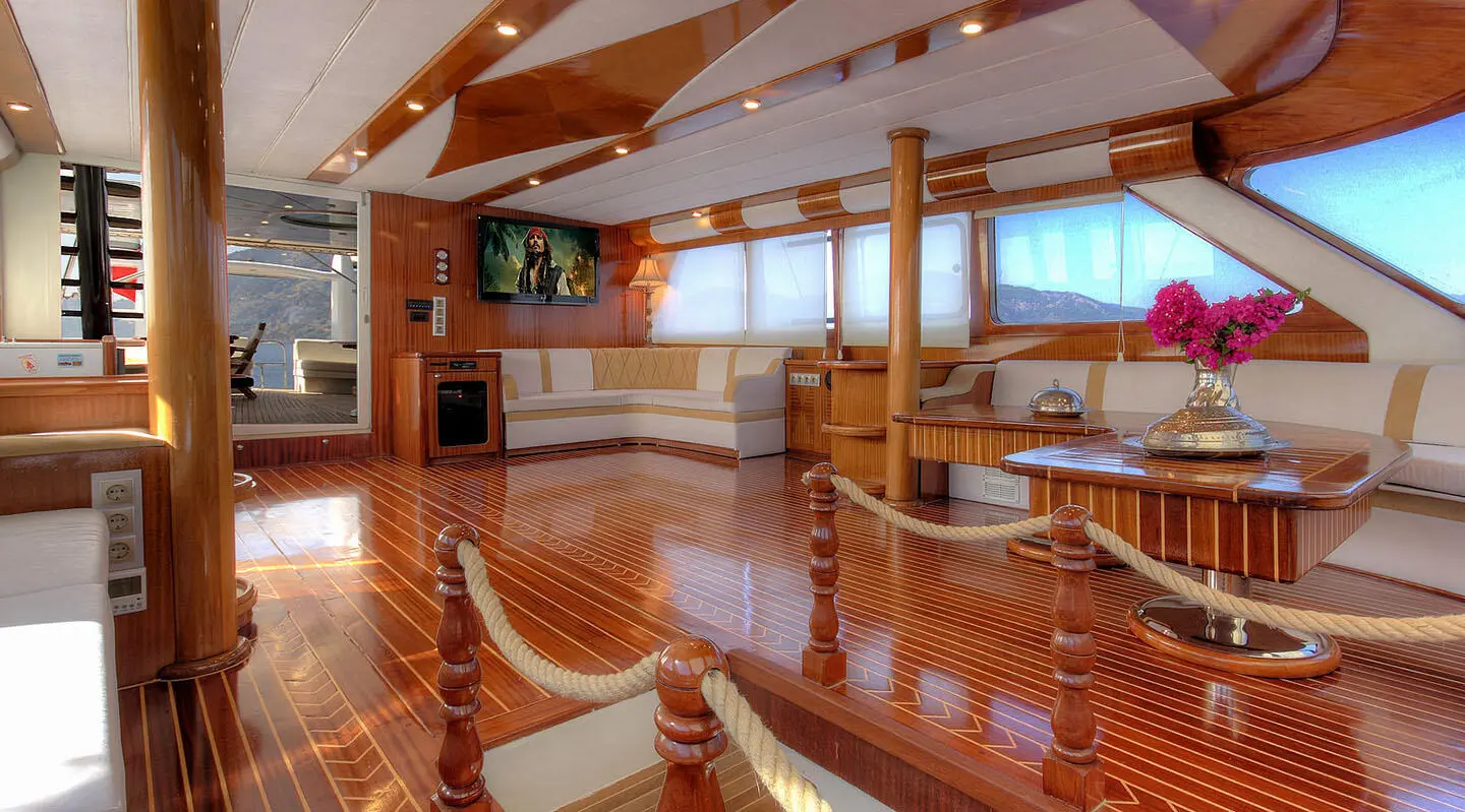 Luxurious gulet saloon with wooden furniture, seating, and TV interior