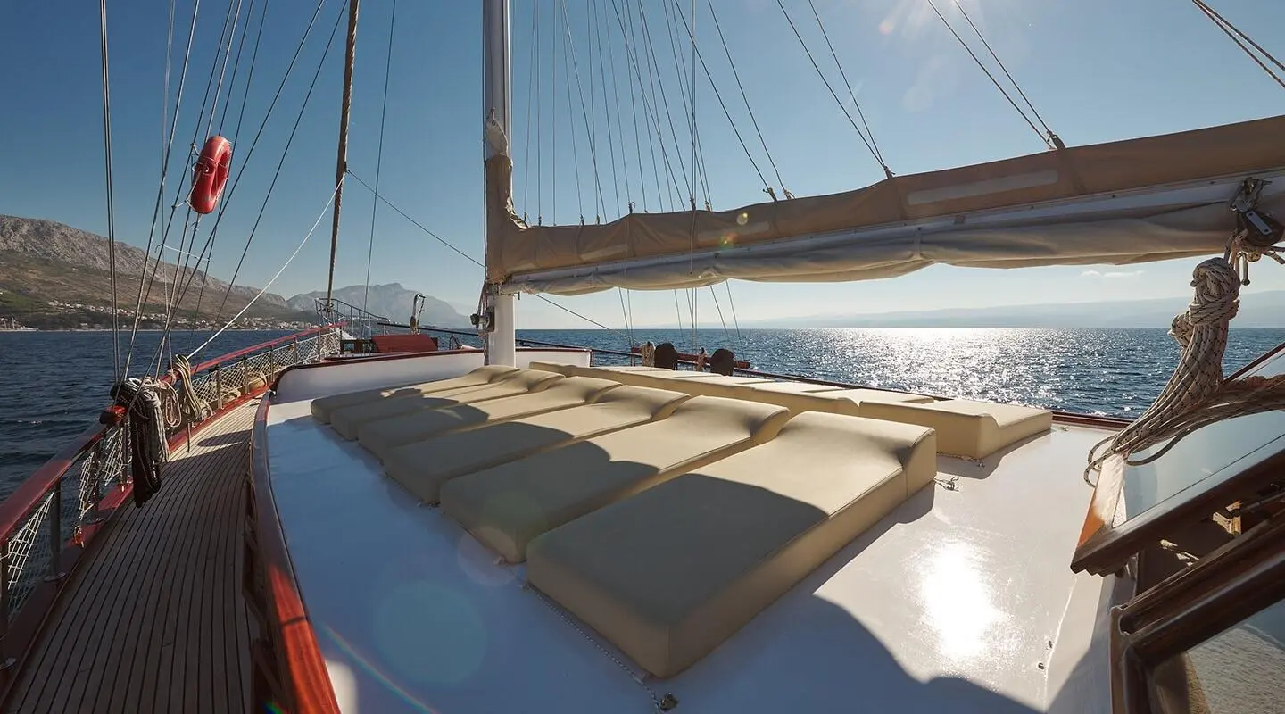 Sunlit yacht deck with beige cushions overlooking the sea