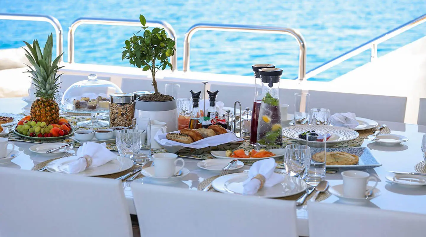 Alalya yacht dining setup on deck with white tablecloths and sea view