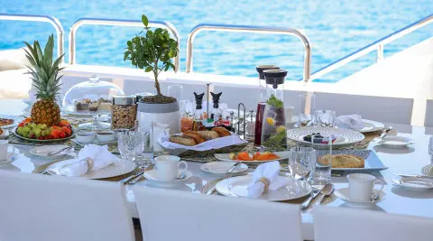 Alalya yacht dining setup on deck with white tablecloths and sea view