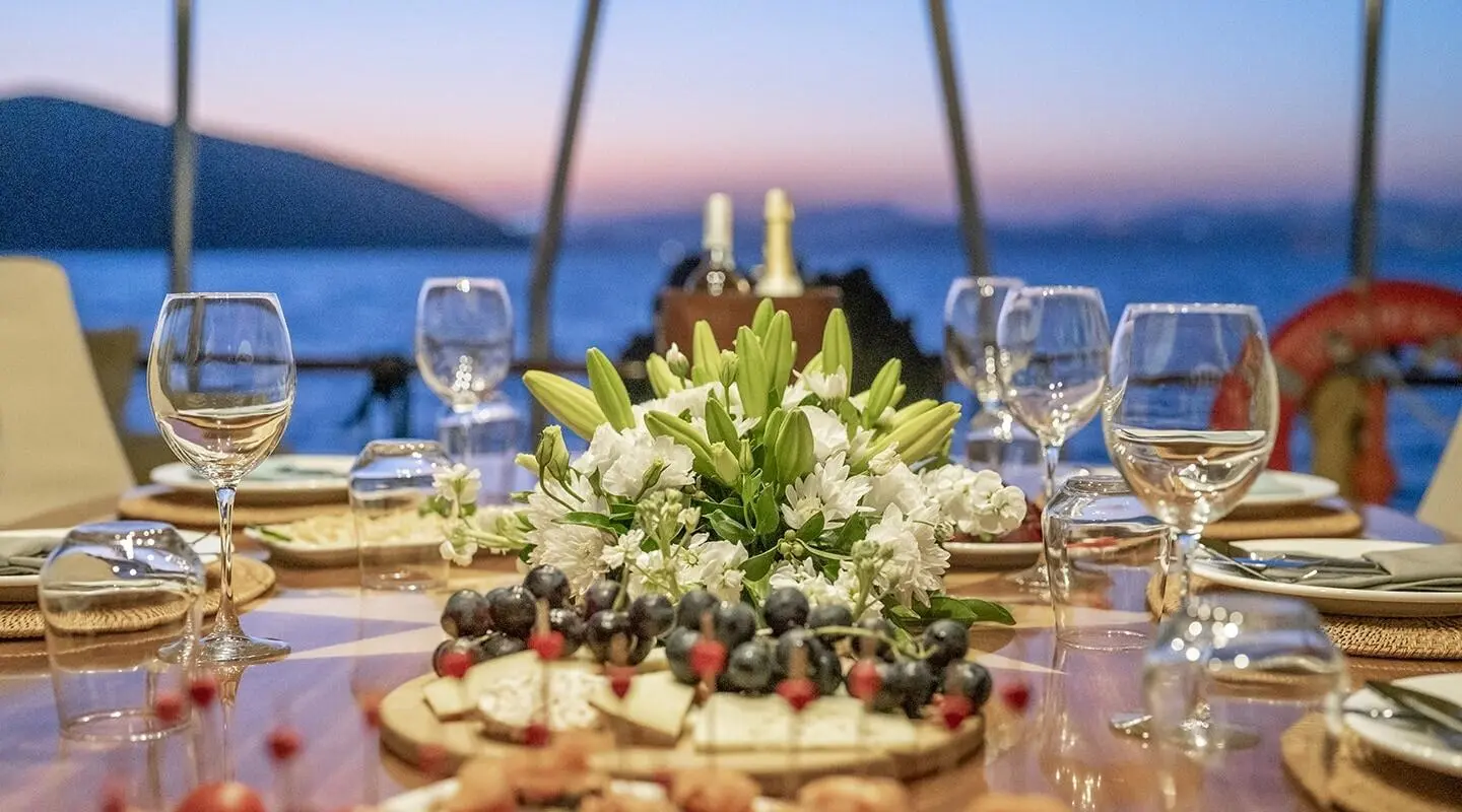 Queen Of Sea luxury gulet at sunset with elegant table set and floral centerpiece