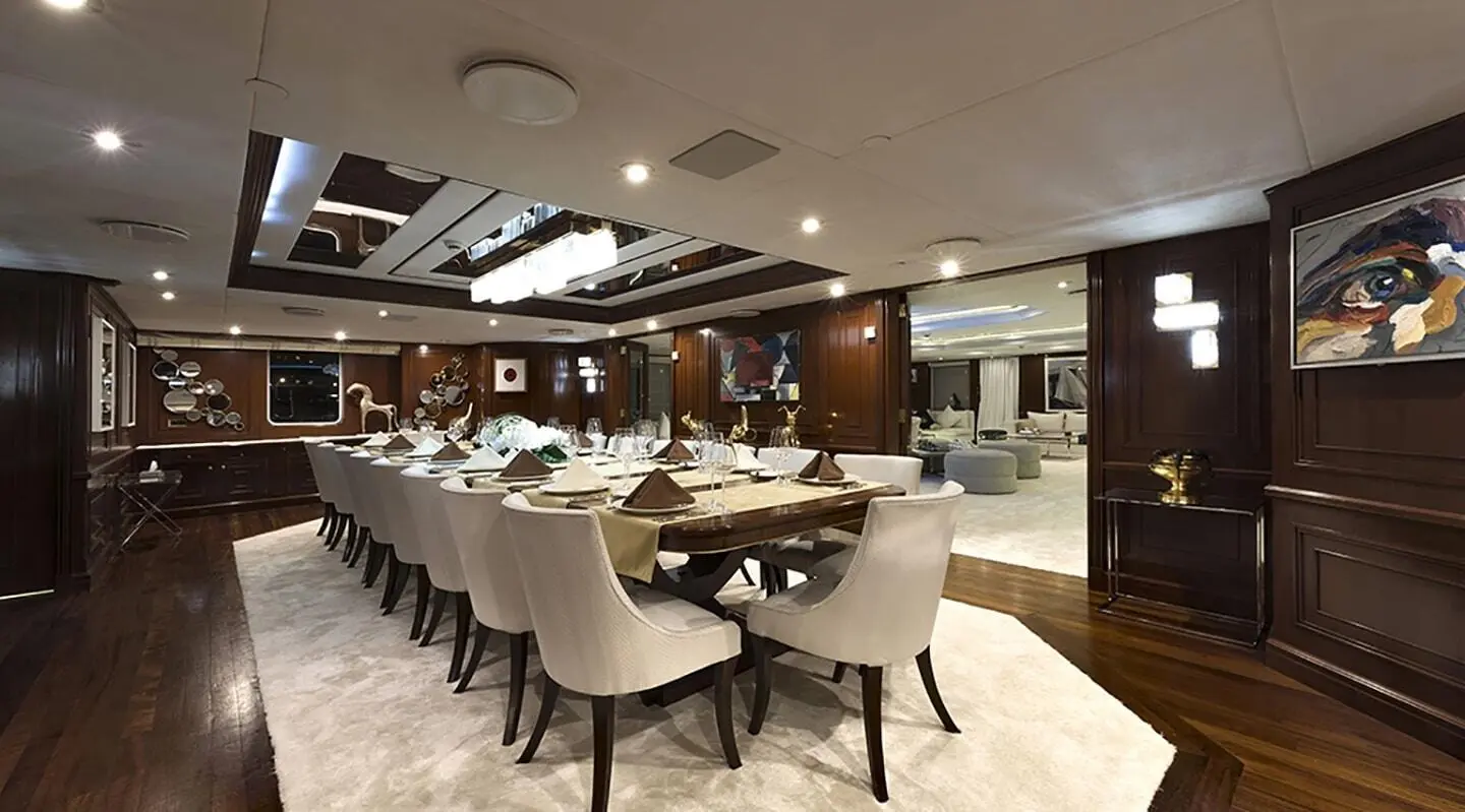 Chakra yacht dining area with long table, beige chairs, and warm lighting