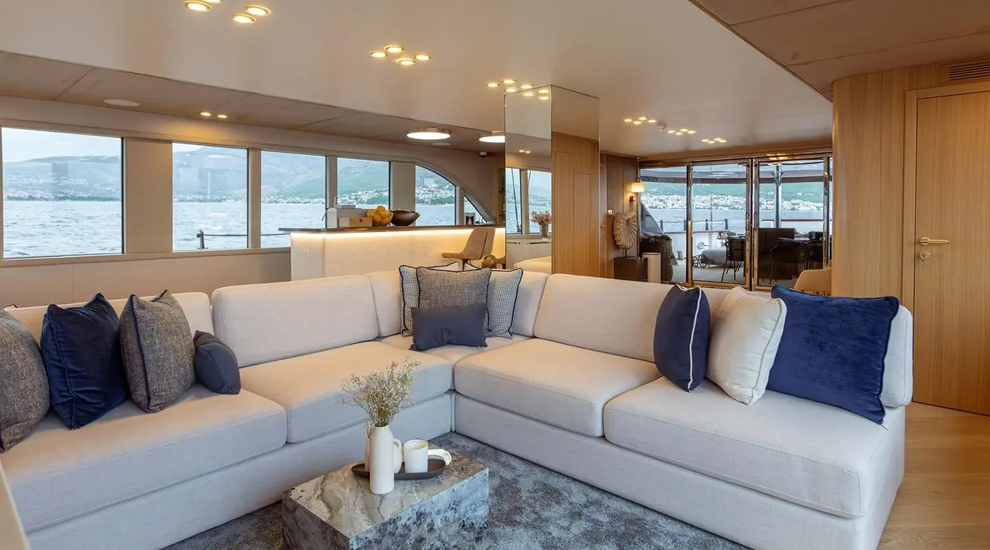 Luxe yacht Scorpios interior with white sectional seating and glass coffee table