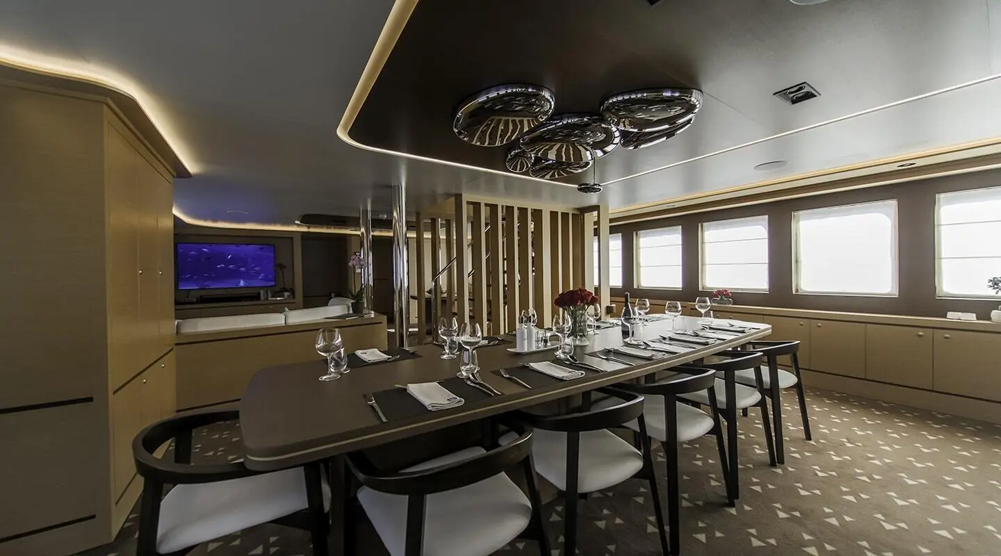 Omnia yacht interior dining area with large windows and sunset glow