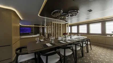 Omnia yacht interior dining area with large windows and sunset glow