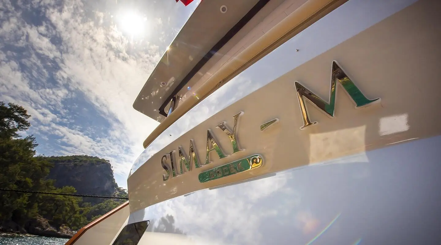 Close-up of Simay M yacht stern with name on hull and water spray