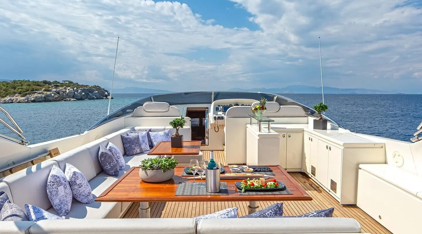 Deck seating on a luxury yacht with a sunlit table setup and ocean view