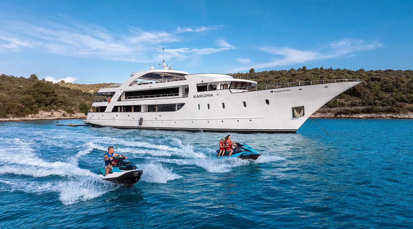 Karizma luxury yacht anchored on blue sea with people kayaking nearby
