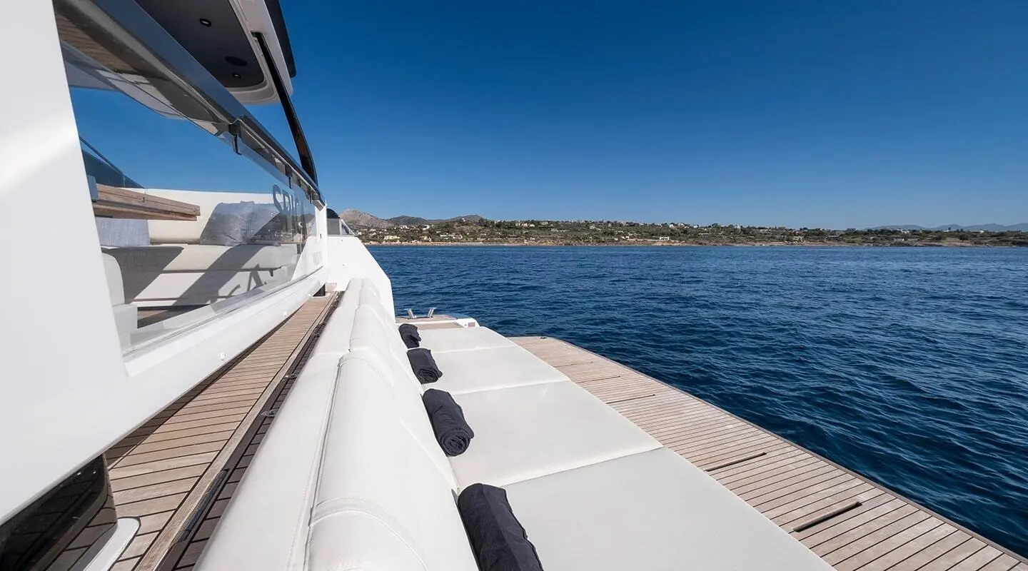 View along the yacht deck with sun loungers and calm blue sea