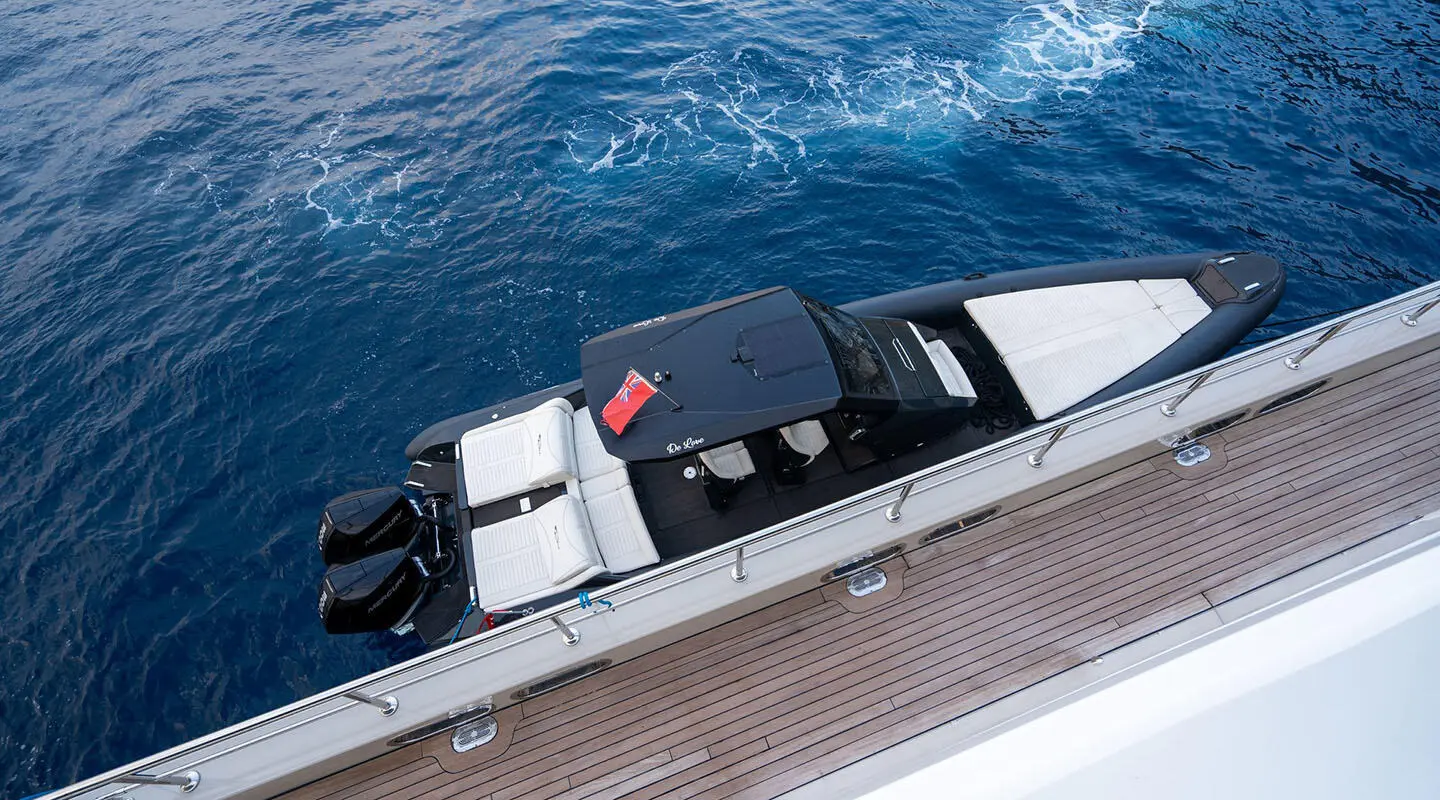 A sleek De Love yacht seen from above docking alongside a pier with blue ocean water nearby
