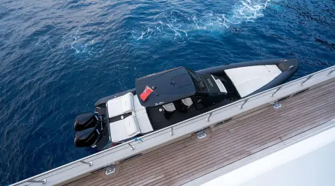 A sleek De Love yacht seen from above docking alongside a pier with blue ocean water nearby