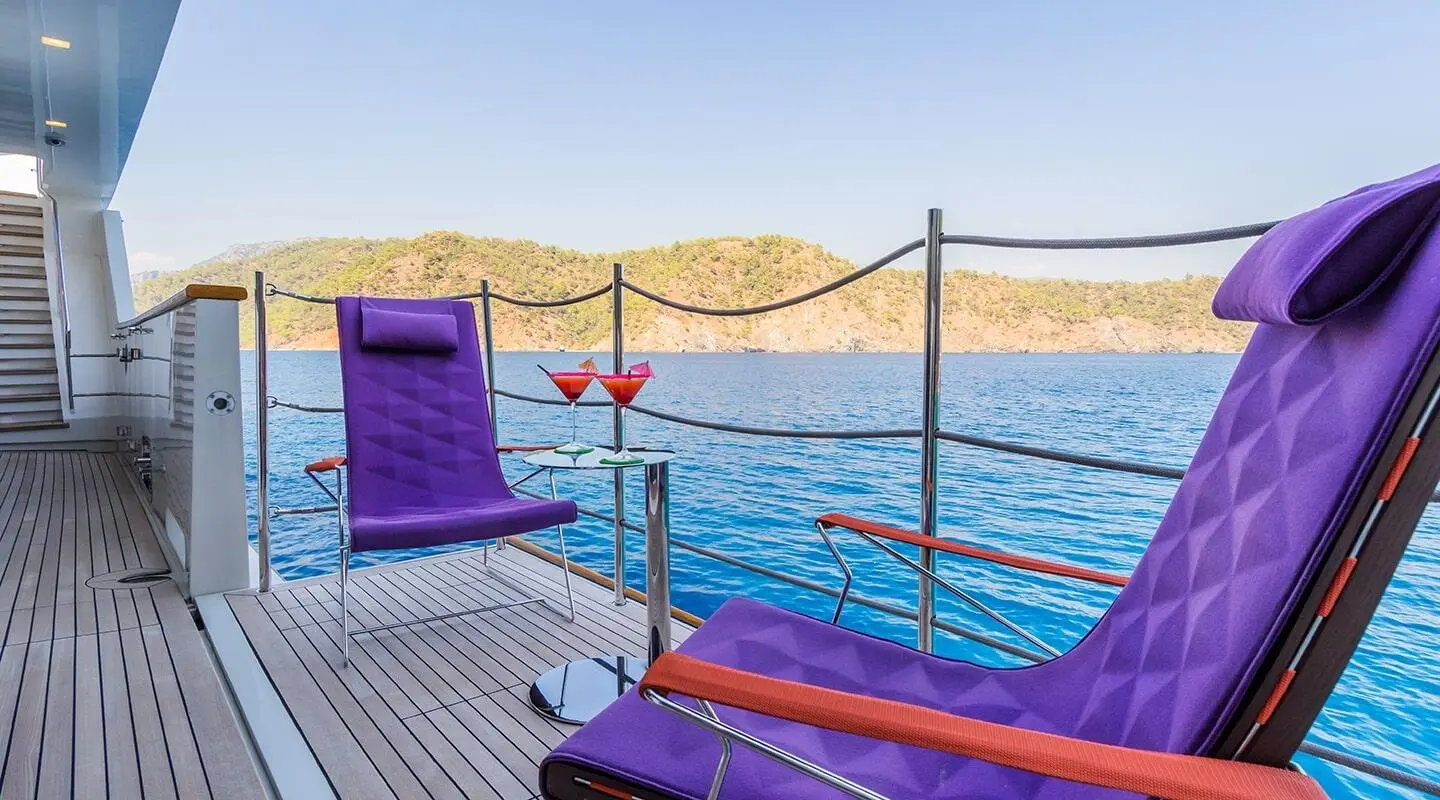 Takara One yacht deck at sunset with purple loungers by clear blue sea