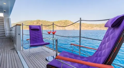 Takara One yacht deck at sunset with purple loungers by clear blue sea
