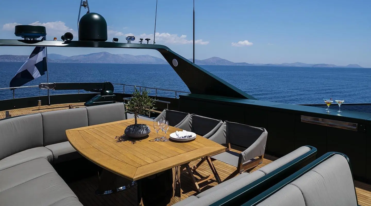 Luxury yacht dining deck at sunset with wooden table and seating