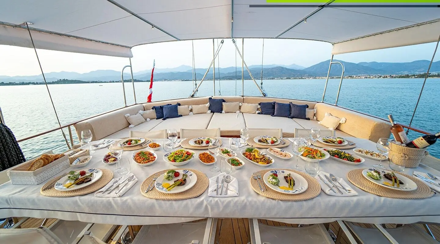 Yacht Happy Days dining deck with a long table set for meals at sunset sails