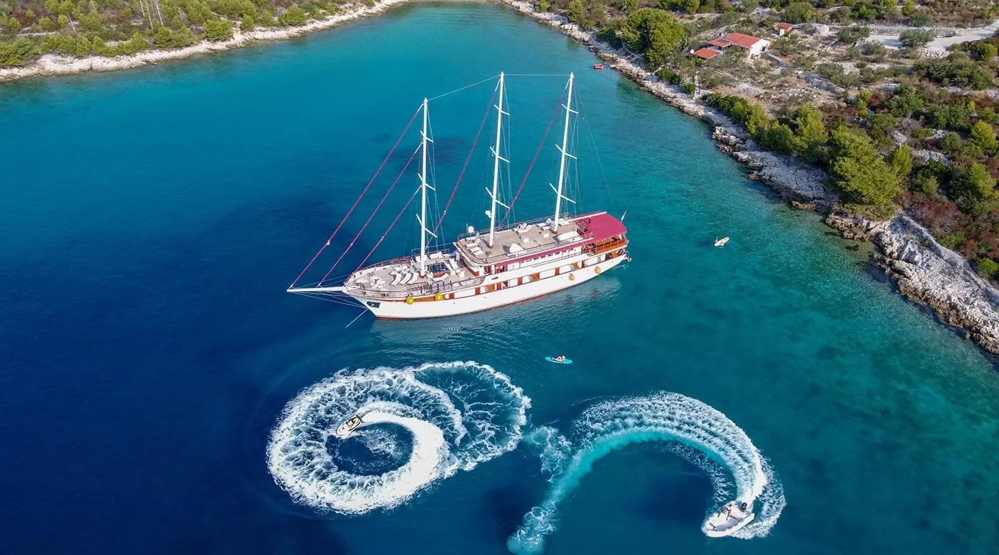 Amorena yacht anchored in turquoise water with water toys nearby.