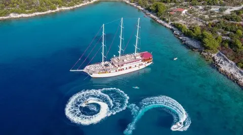 Amorena yacht anchored in turquoise water with water toys nearby.