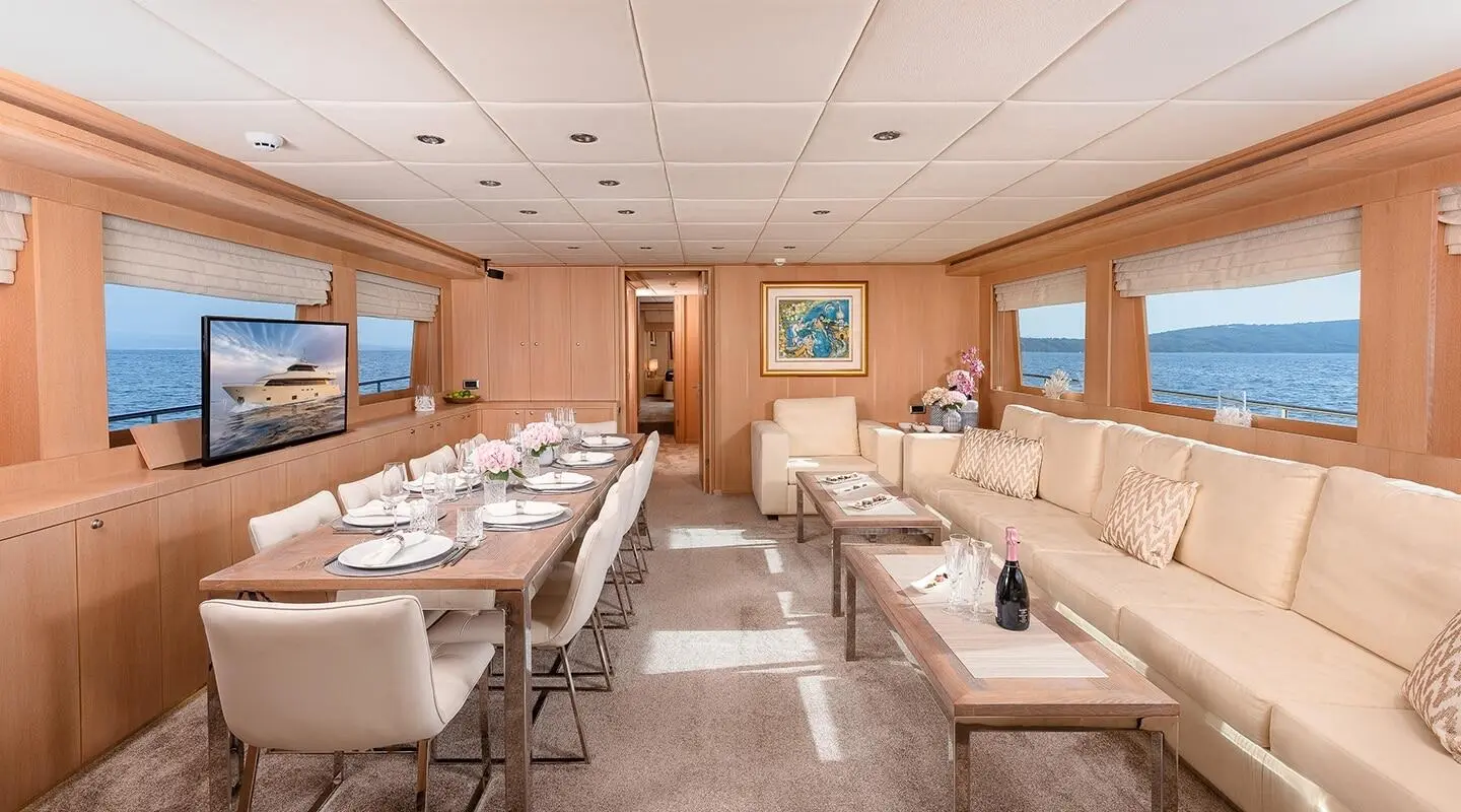 Interior of Grace yacht salon with long beige seating, table setup, and windows