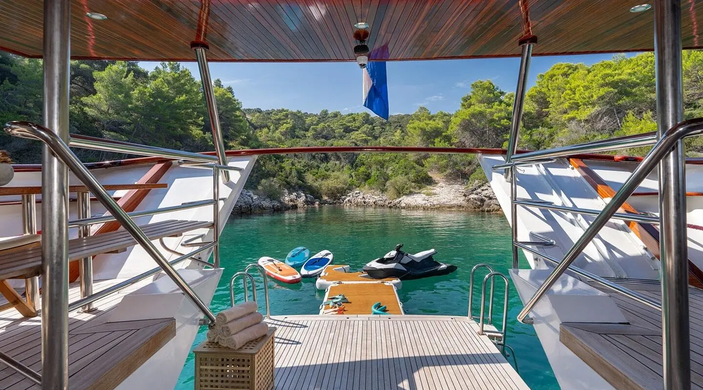 View from a yacht swim platform of Barbara overlooking turquoise water and rocky shoreline