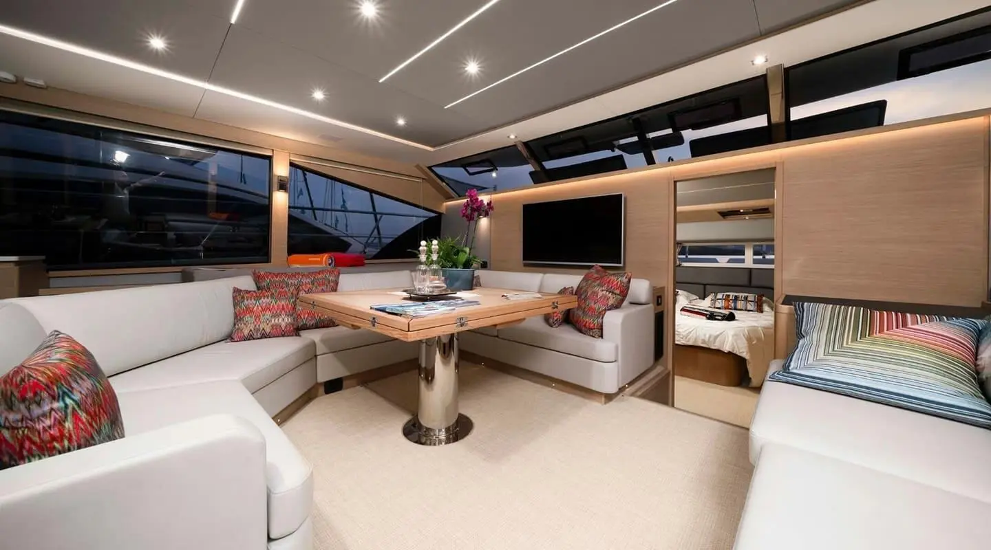 Luxurious yacht salon interior at sunset with seating, tables, and shelves