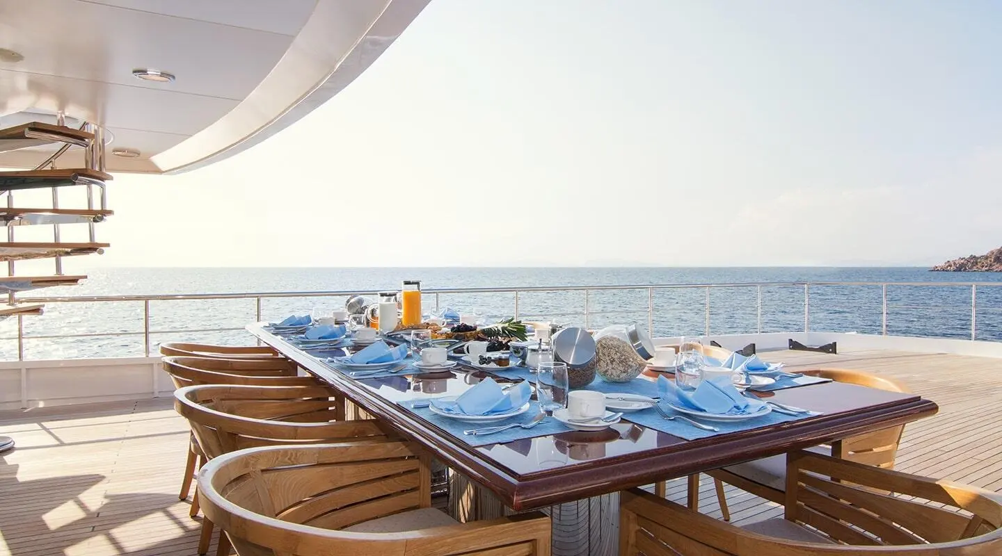 O'Natalina yacht dining area at sunset with blue tablecloths and sea view
