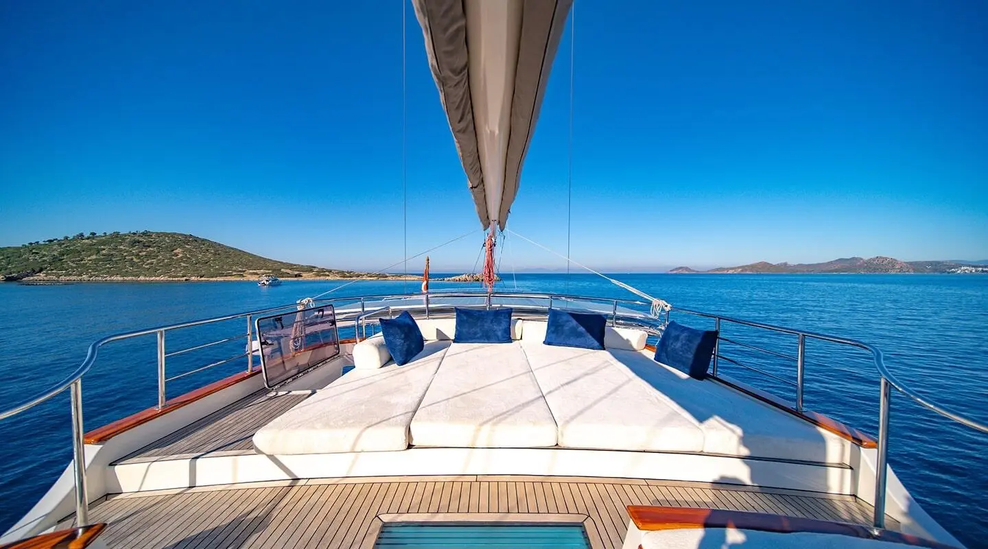 View from the yacht deck toward blue sea, sunlit teak seating on Double Eagle