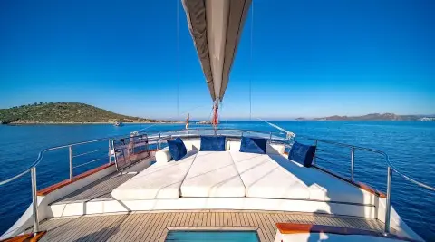 View from the yacht deck toward blue sea, sunlit teak seating on Double Eagle
