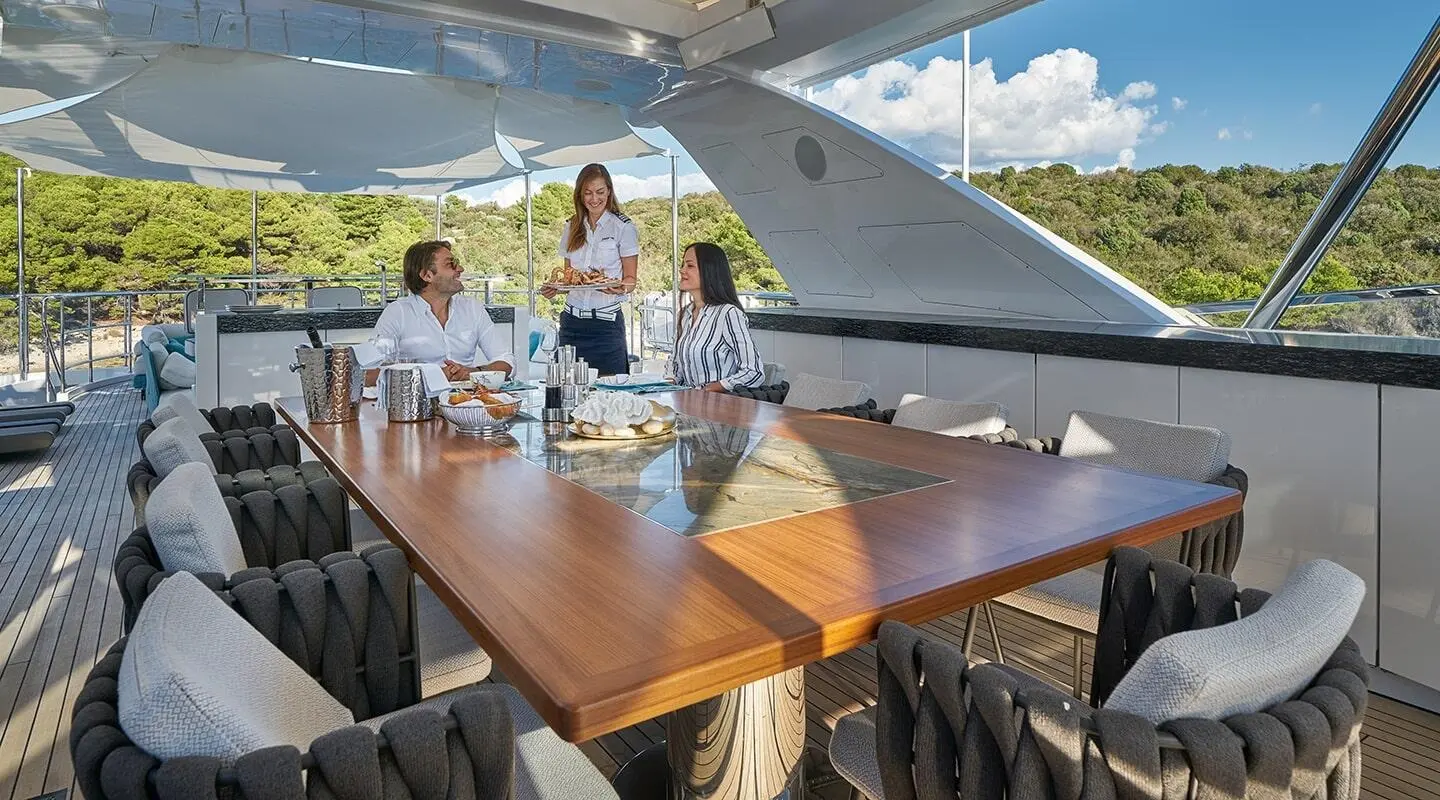 Yacht Happy Me with a wooden dining table under a canopy on deck