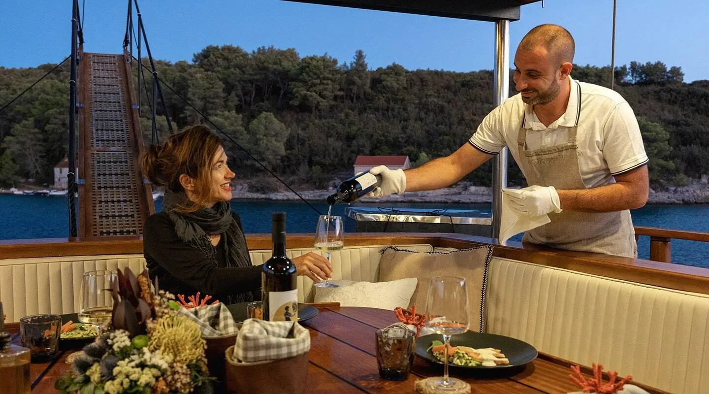 Yacht Aborda at sunset with people dining on deck and sea view