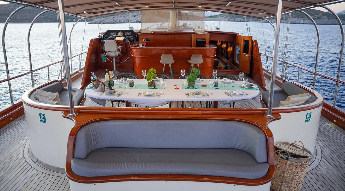 Open deck with a long dining table and seating area on La Bella Vita gulet aft deck