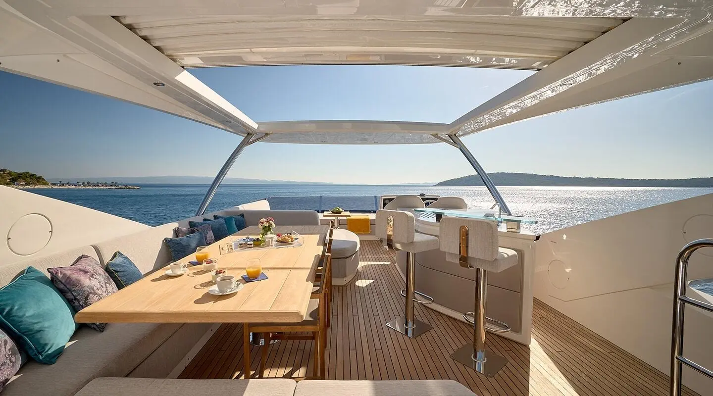 Yacht Hideaway upper deck with wooden floor, seating, table, and ocean view