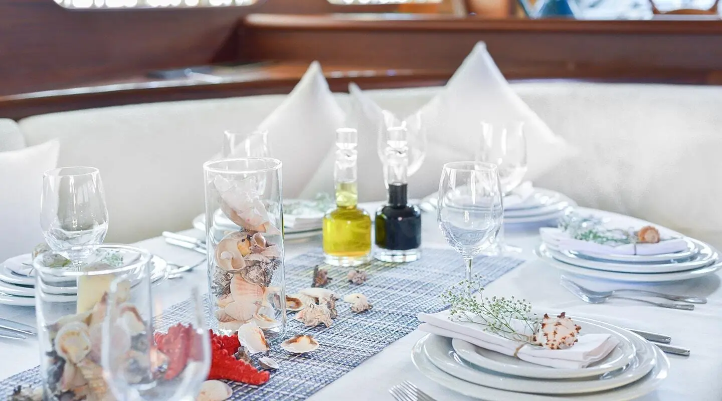 Elegant yacht dining setup on deck with white napkins and glassware at sunset