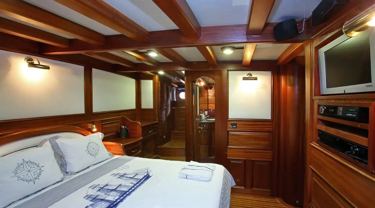 Wood-paneled yacht cabin with bedside lights and doors, warm interior