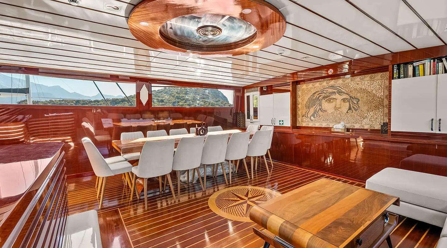 Esma Sultan yacht interior with polished wooden floor, white and brown seating, and a long dining table