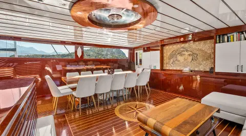 Esma Sultan yacht interior with polished wooden floor, white and brown seating, and a long dining table