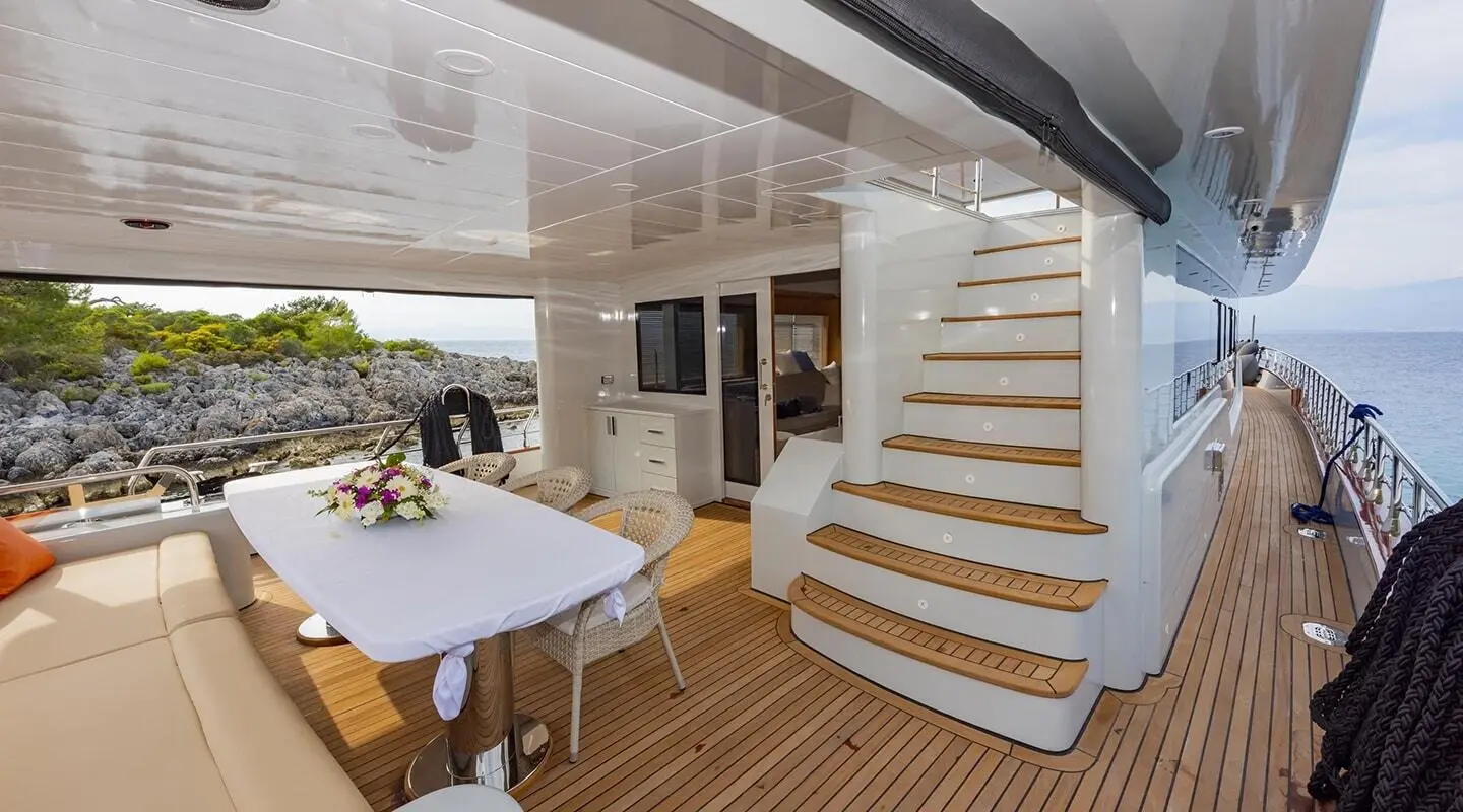 Yacht Simay M deck seating area with table, stairs, and sunlight