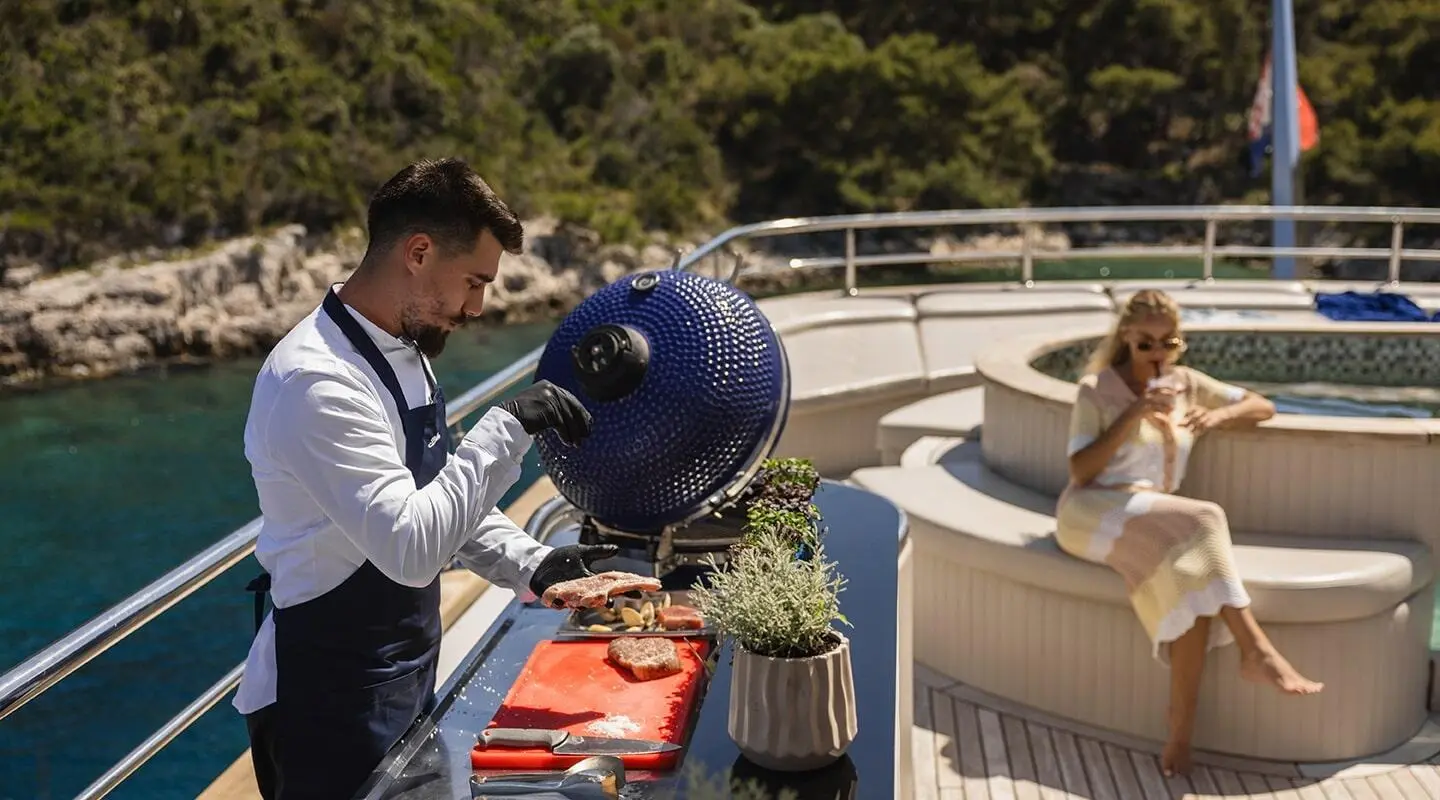 Bella yacht with crew handling a blue fender on a sunny deck