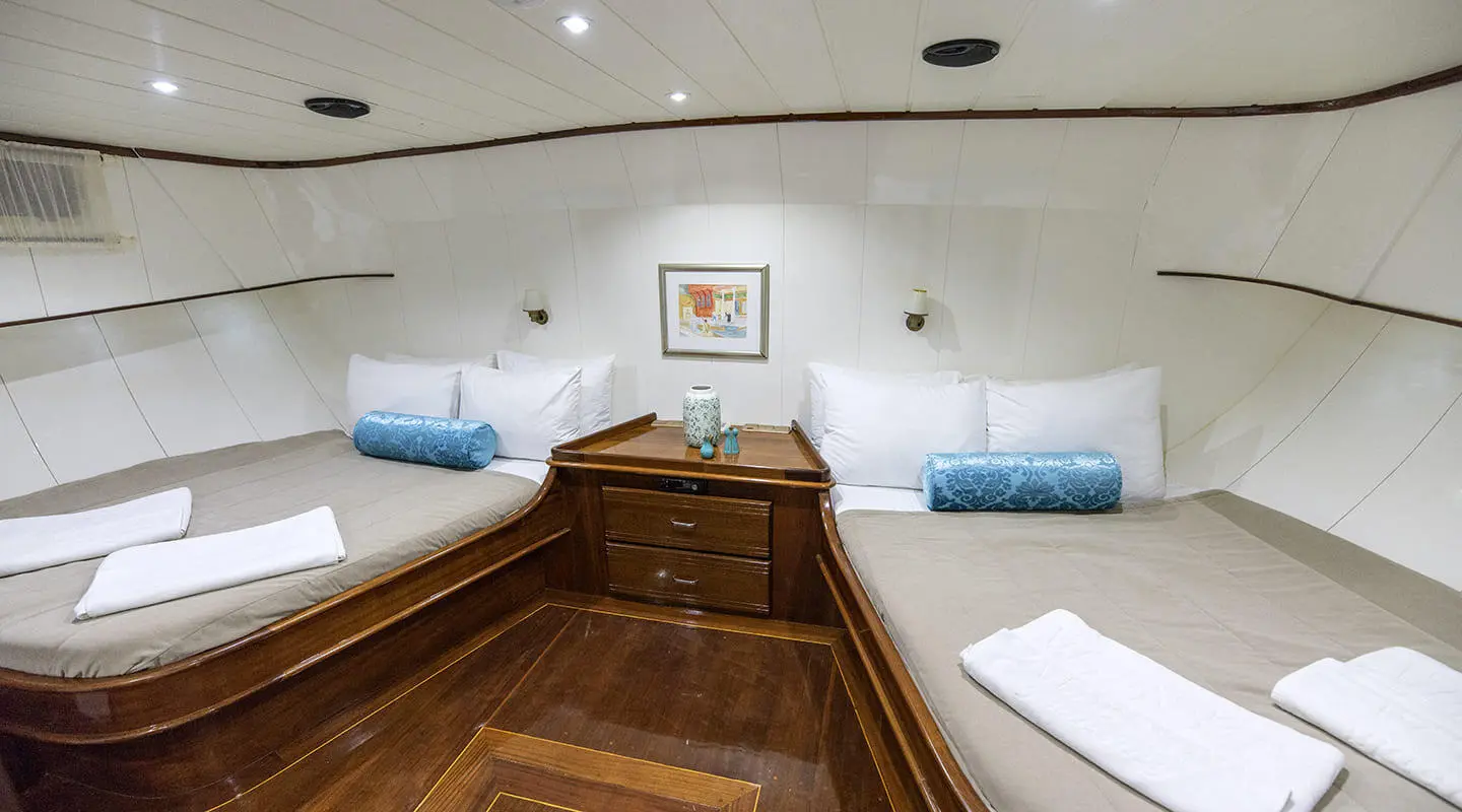 Interior of Faralya yacht saloon with wooden flooring and blue cushions