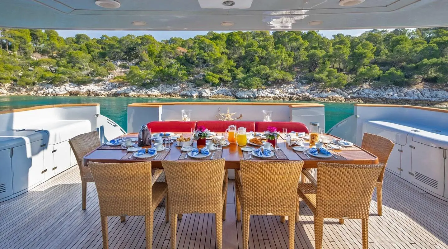 Glaros yacht daytime dining table on deck with chairs and pool in background