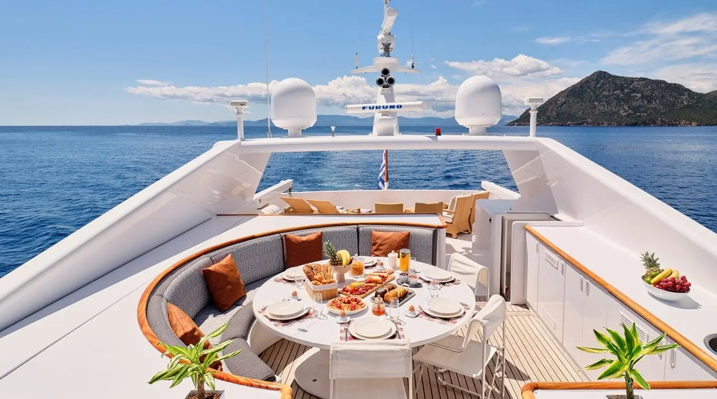 Mobius yacht deck dining area with table set, seating, sunlit sea view